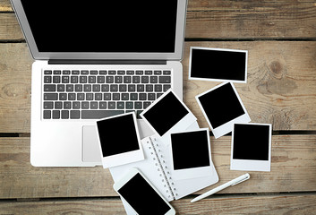 Laptop, notebook and photos on wooden background