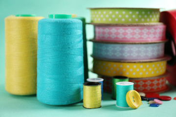 Many ribbons and sewing accessories on color background