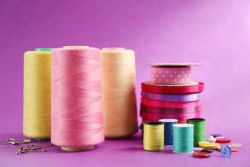 Many ribbons and sewing accessories on color background