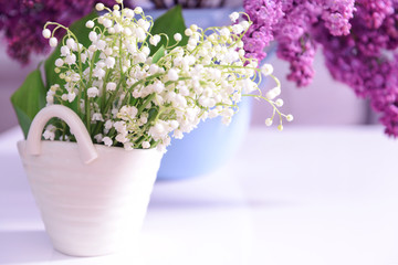 Lilac and may-lily bouquets on white table