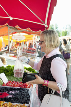 Finland, Helsinki, Kauppatori, Smiling senior woman buying strawberries at street market