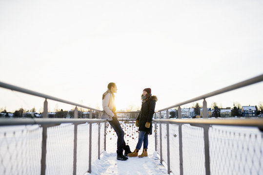 Sweden, Vasterbotten, Umea, Young couple standing face to face on footbridge
