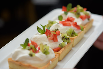Tarts with whipped cream and strawberries and mint leaves