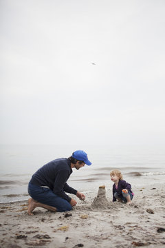 Sweden, Skane, Osterlen, Dad building sand castle with his daughter (2-3)
