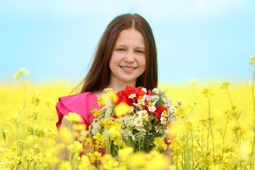 Sweet girl in meadow with wild spring flowers