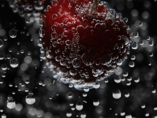 Cherry in water with bubbles close up on dark background
