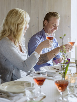 Sweden, Smiling man and woman raising wine glasses in celebratory toast