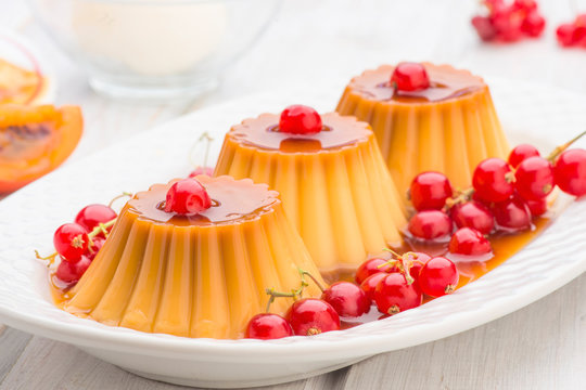 flans with red currants and syrup in white tray
