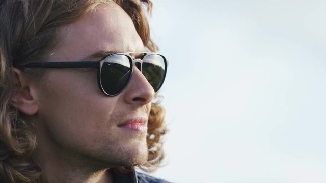 4K Handsome man in sunglasses looking off camera, with space for text
