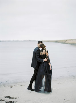 Sweden, Halland, Varberg, Young formally dressed couple walking along beach