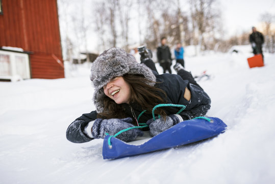 Happy young woman sliding on toboggan in winter