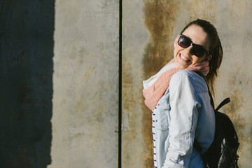 Urban portrait of woman wearing sunglasses, smiling at the camer