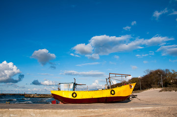 Naklejka na ściany i meble Yellow fishing boat moored on the beach