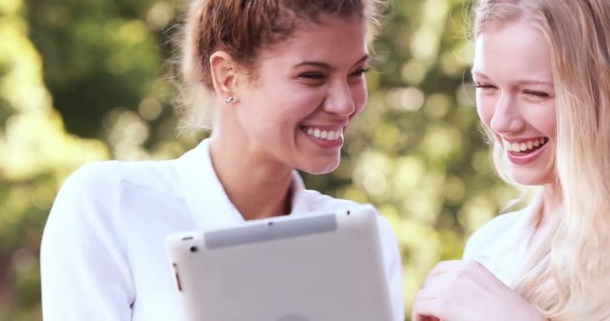 Hip friends using tablet outdoors