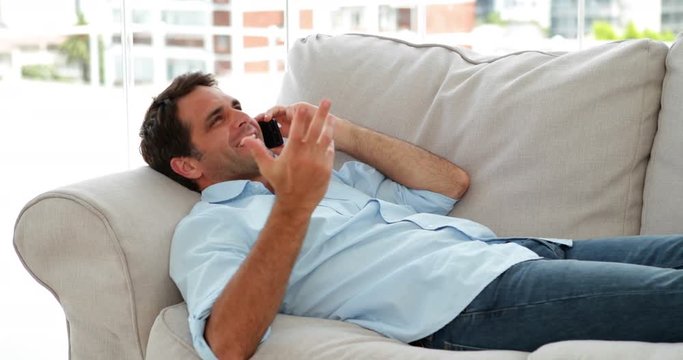 Casual man lying on the sofa chatting on the phone