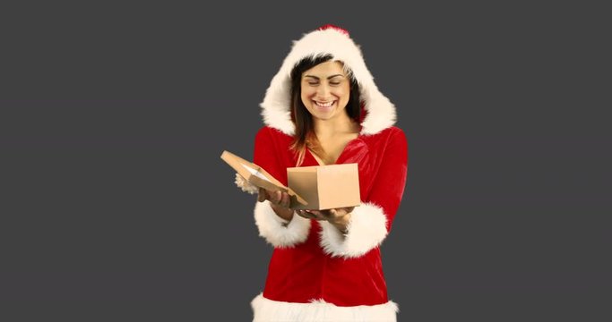 Sexy girl in santa costume opening a gift on grey background