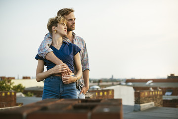 Germany, Berlin, Young couple standing on rooftop against sky