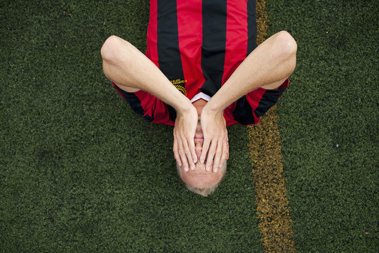 Sweden, Soccer player lying down on soccer field, head in hands