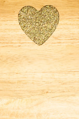 Fennel dill seeds heart shaped on wooden board