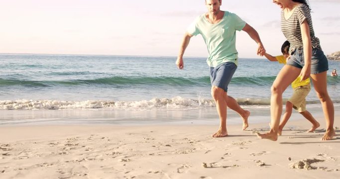 Happy family walking on the sand in slow motion