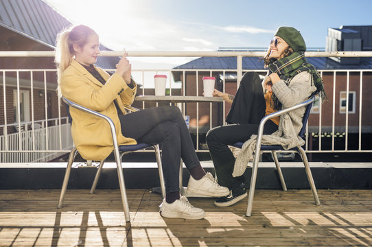 Sweden, Vasterbotten, Umea, Two young women sitting outdoors