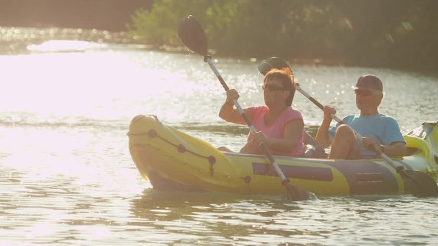 SLOW MOTION: Happy smiling couple enjoying summer sunset canoeing