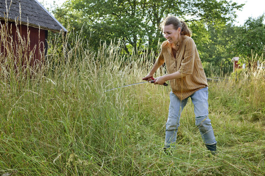 Farmer cutting grass in field