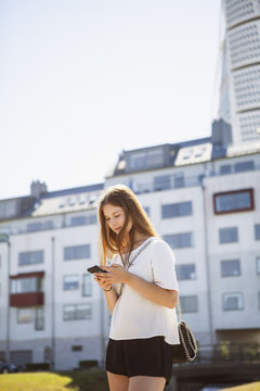 Sweden, Skane, Malmo, Teenage girl (16-17) using smart phone in Vastra Hamnen neighborhood