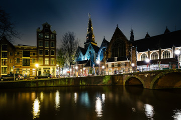 Naklejka premium The Oude Church and a canal at night, in Amsterdam, The Netherla