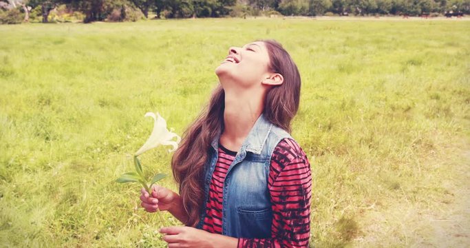 Pretty brunette smelling a flower on a sunny day