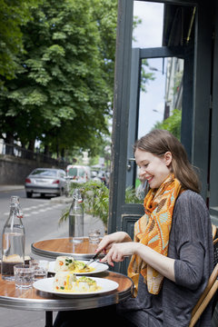 Smiling young woman having lunch at outdoor restaurant
