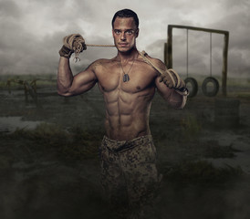 Shirtless muscular soldier in a training swampland.