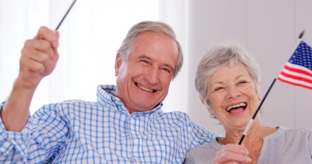 Senior couple holding american flag - Powered by Adobe