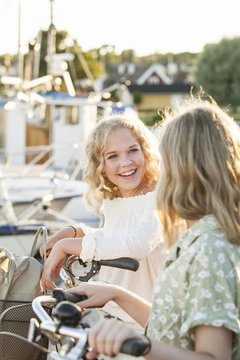 Sweden, Blekinge, Hallevik, Two teenage girls(14-15, 16-17) with bicycles at marina bay
