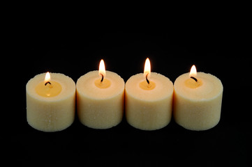 Fototapeta na wymiar candle flame fire of white candles in a row on black background