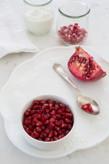 Pomegranate seeds and quarter with yogurt play on white (F/32)