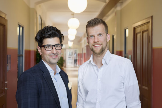 Portrait of smiling men standing in corridor