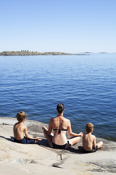Mother and sons practicing yoga on the seaside