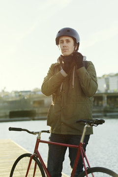 Sweden, Sodermanland, Stockholm, Sodermalm, Slussen, Outdoor portrait of mid adult man tying helmet strap
