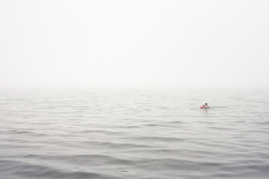Sweden, Gotland, Ljugarn, Man and boy (4-5) swimming in foggy sea