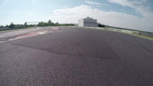 LOW ANGLE VIEW: Race car competing and driving fast on race track lap