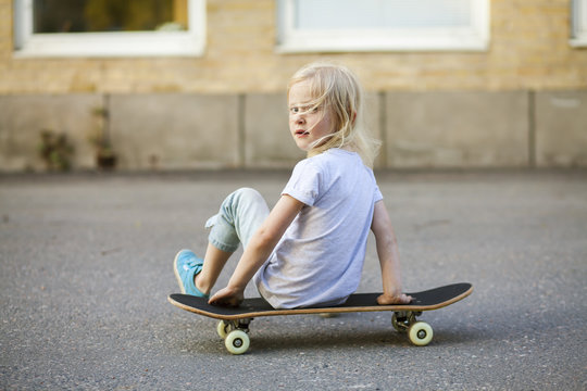 Portrait of girl sitting on skateboard