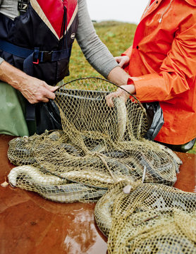 Midsection of fishermen holding fishing net outdoors