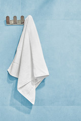 White towel hanging on a wall in bathroom.