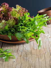 fresh green salad with arugula tomatoes and cucumbers on a wooden table