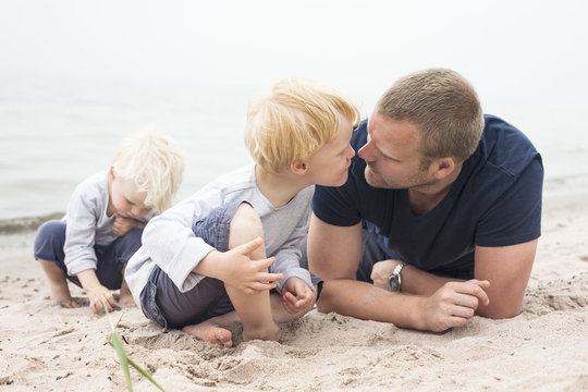 Sweden, Gotland, Ljugarn, Two boys (2-3, 4-5) spending time with man on beach