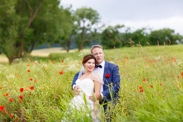 Happy wedding couple in pink poppy field