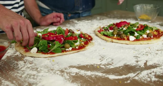 Close up view of a couple preparing pizza in the kitchen