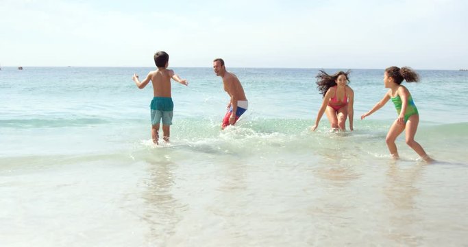 Happy family playing with waves on the beach