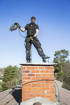 Sweden, Sodermanland, Nacka, Mid-adult man cleaning chimney 